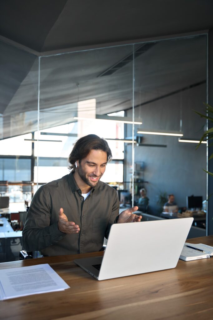Happy business man in earbuds working looking at laptop having virtual meeting.