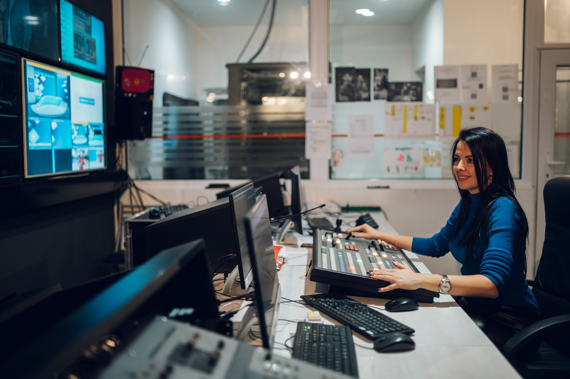 Middle aged woman working on a tv station as a producer in a broadcast control room