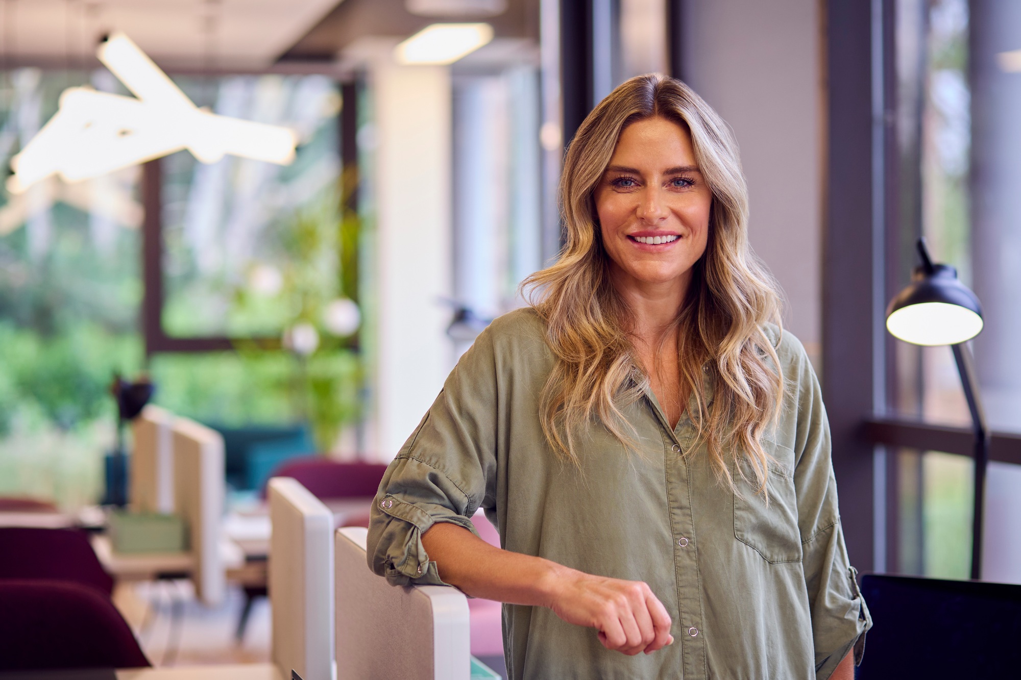 Portrait Of Mature Businesswoman Standing By Partition In Open Plan Office